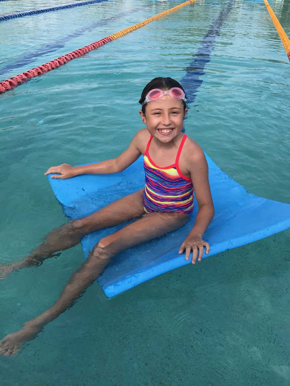 Ella relaxes after some racing and fun during Little Kickers before school, at the Rainbow Beach Aquatic Centre