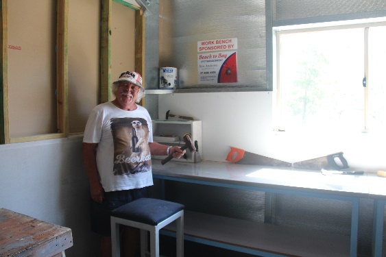 Bryan Phillips (Shed Manager) standing next to the workbench sponsored by Ben and Cassie Andrews of Beach to Bay Pest Management