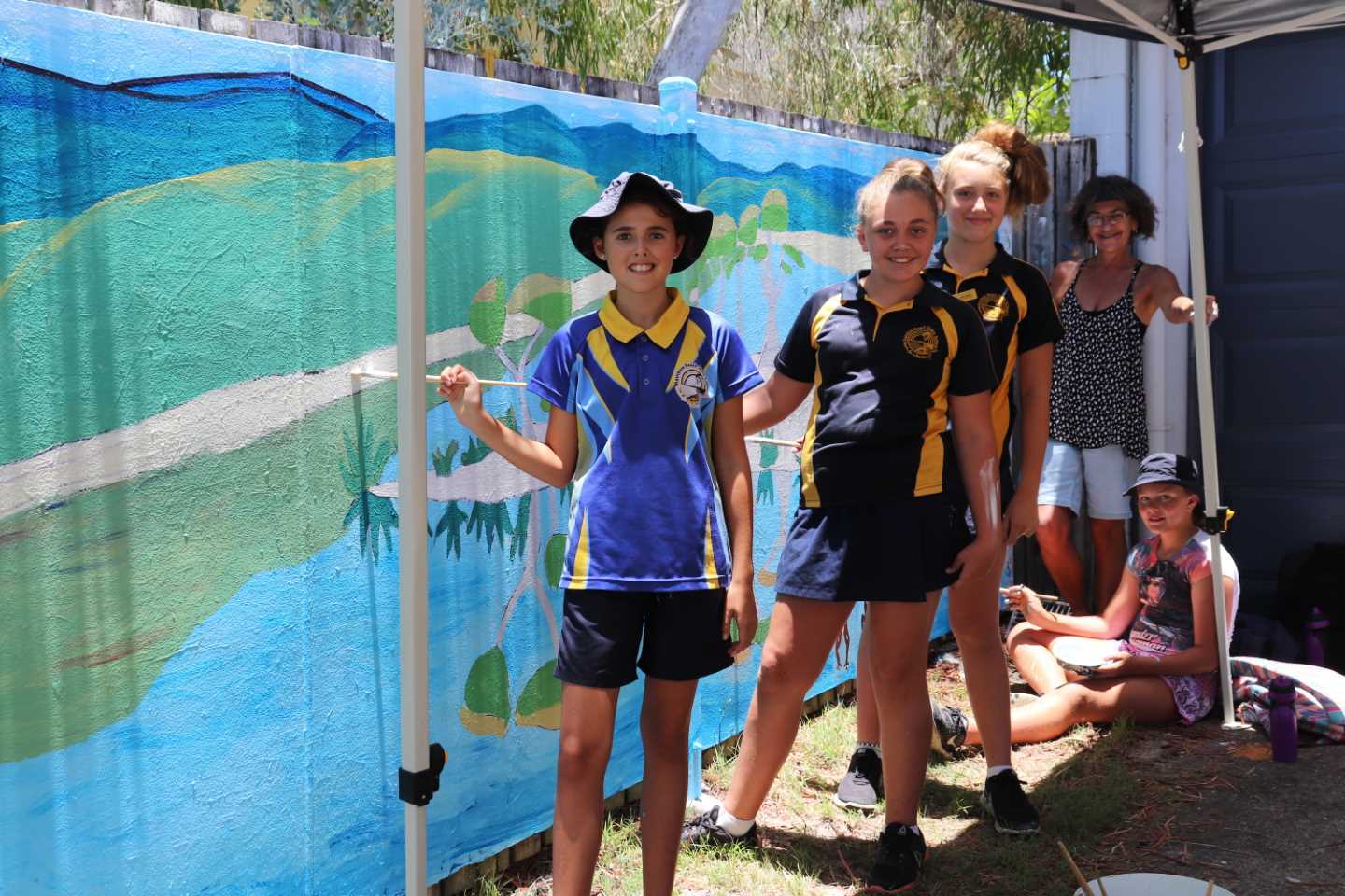 Mrs Lane helps Tia, Janae, Laila and Luxie paint the Police Beat Mural for 2019