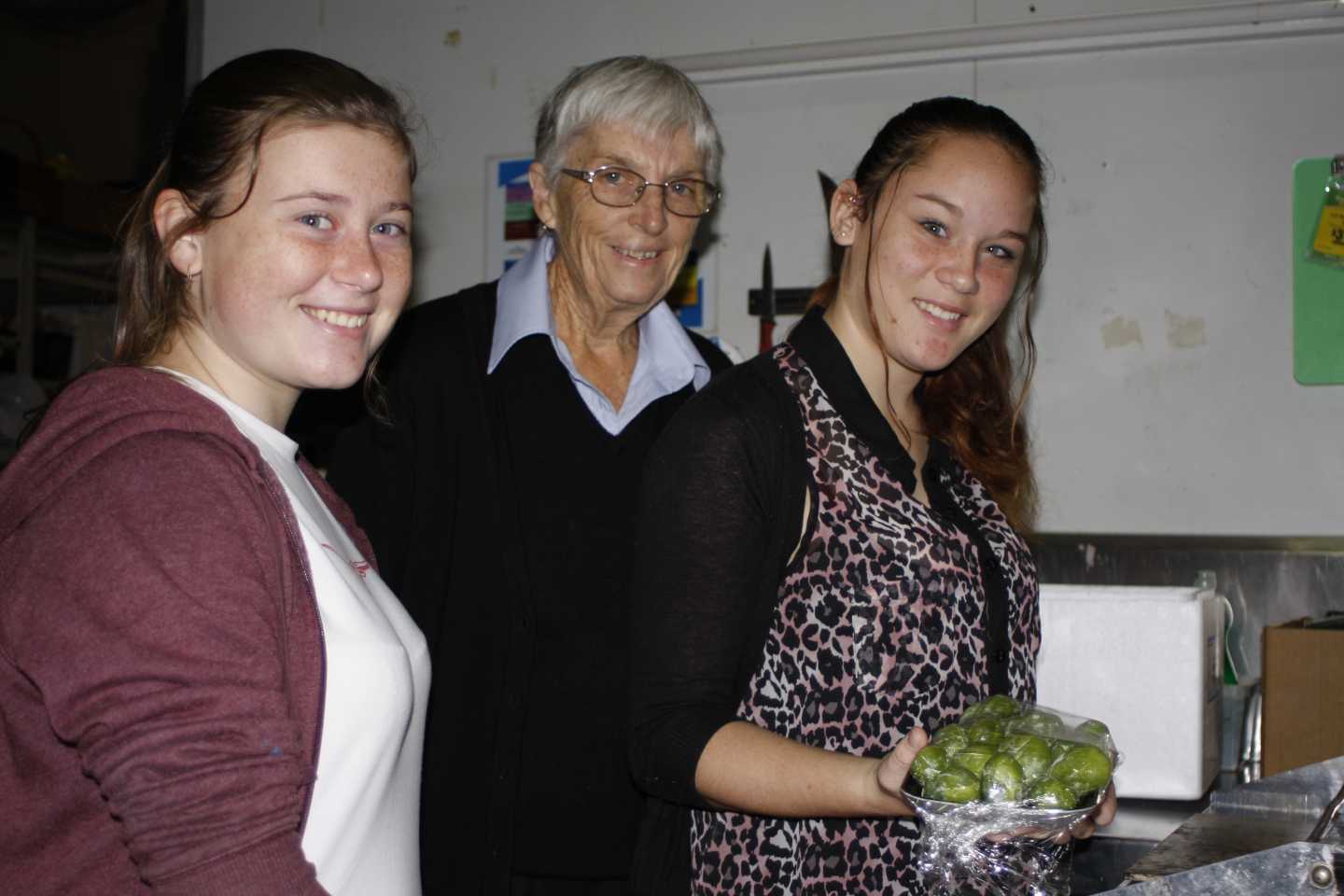 Tin Can Bay IGA's Ruth Steinsch trains Ally Duckworth and Paige Edmonds in the wrapping machine to keep produce well-presente