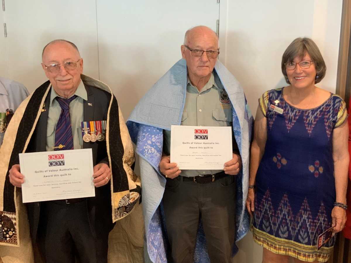 Locals, Joe Casey and Barry Hogan, are awarded their handmade quilts by Barbara Kenny of Quilts of Valour