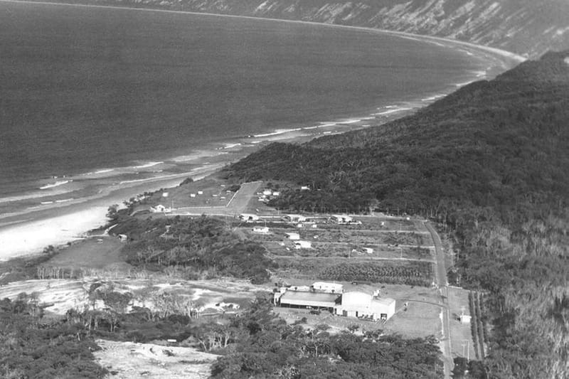 An aerial photo of Rainbow Beach from 1965 showing the Mineral Sands Building, the three mining houses, the Surf Club, Phil R
