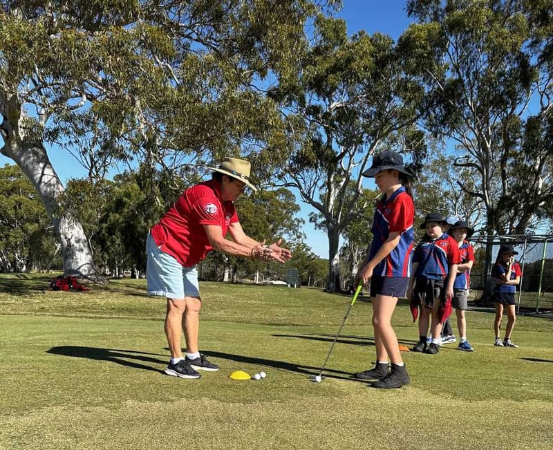 Junior Golfing Coordinator Janet Reibel helps Mary with her putting. Photo credit: Tin Can Bay P-10 School